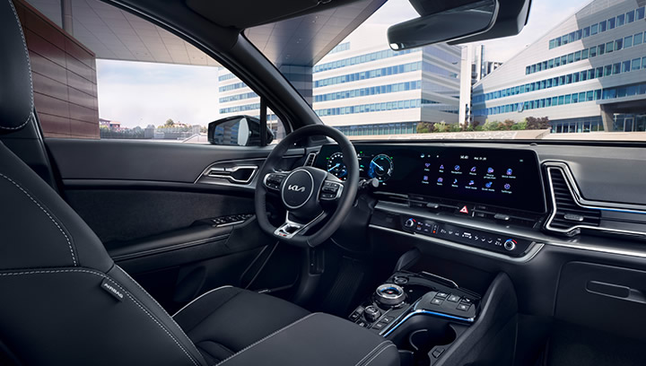 Kia EV9 GT, grau, Frontansicht, LED-Lichtsignatur, Frau steht auf Fahrerseite